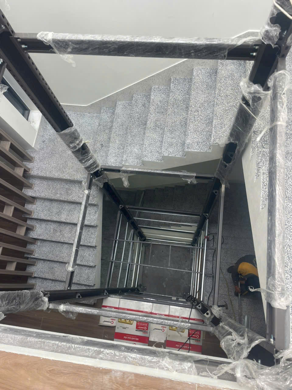 Khung thang máy gia đình đang lắp đặt giữa giếng trời cầu thang trong nhà
